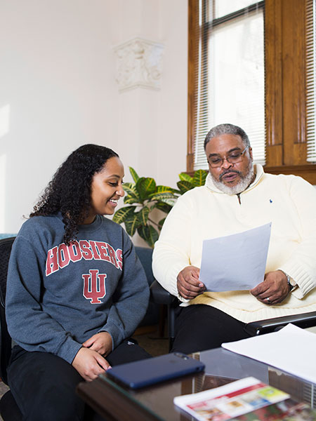 A student (L) sitting next to Groups Scholars Program Director Samuel Young III (R) as they discuss information in a paper packet