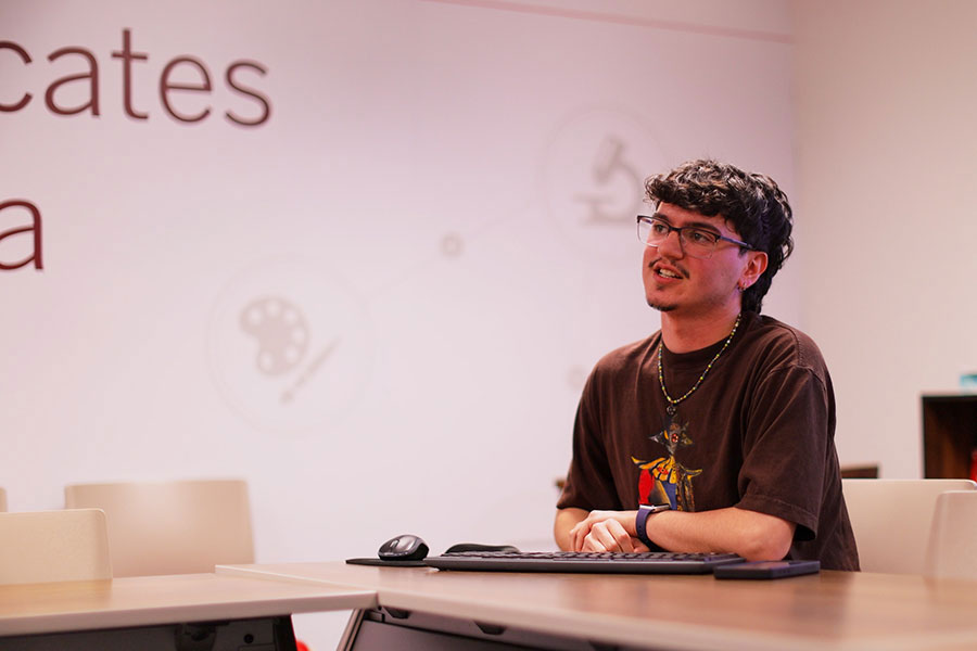 Anthony Brace sits at a table in a classroom.
