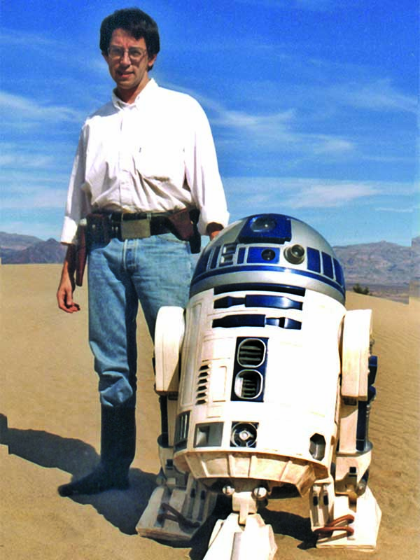 David West Reynolds standing in desert with Star Wars character R2D2