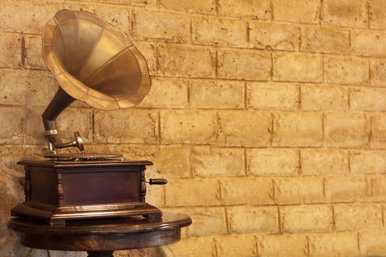 Gold gramophone in front of a golden-yellow brick wall.