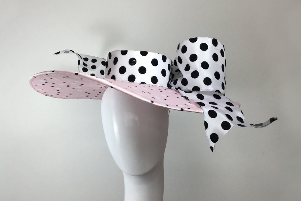 A wide-brimmed polka dot hat featuring a bow.