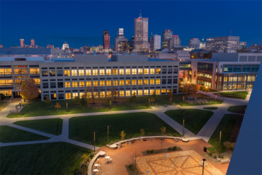 A night shot of the IUPUI campus shows the windows aglow against the backdrop of the Indianapolis skyline.