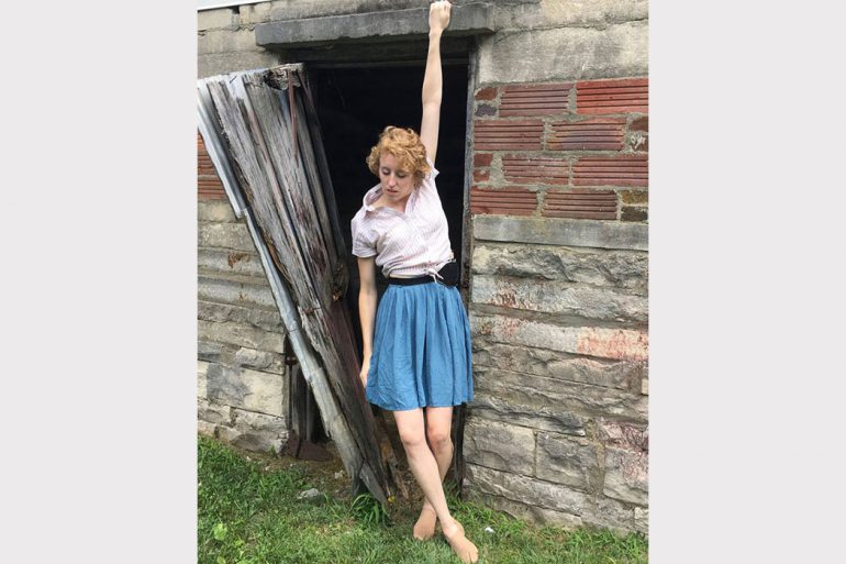 A dancer performs in front of an abandoned building