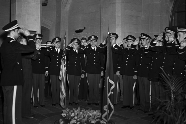 Uniformed service members salute the Memorial Circle Plaque and flags in this black-and-white photo taken circa 1939.