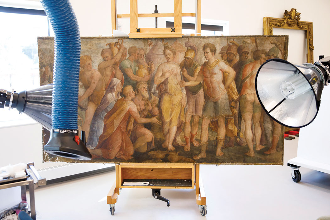An old-looking painting is rigged up on a special stand, surrounded by lights and machines.