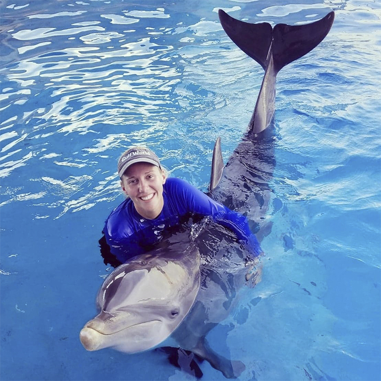 Alexis Miller posing for a photo with a bottlenose dolphin at the Miami Seaquarium