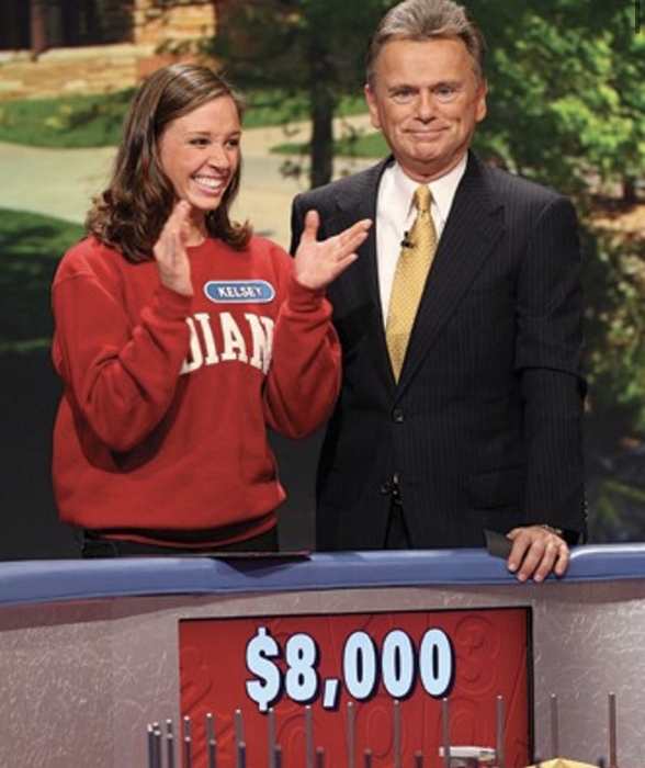 Woman clapping next to a man on a game show set.