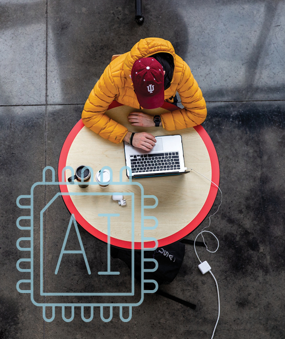 Viewed from above, a student sits at a table working on their laptop. They're wearing a red had with a white IU trident and a yellow-orange puffer jacket. Superimposed on top of the photo is a graphic that looks like a microchip, which has "AI" on it.